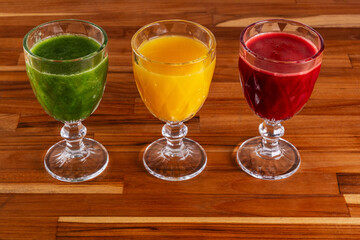 bowls with orange juices, kale with coconut water and apple, and beetroot with orange and carrot