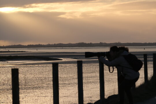 Une photographe au coucher du soleil en bord de mer