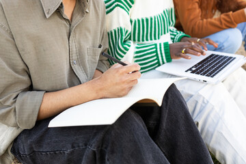 Anonymous multicultural students studying together outdoors