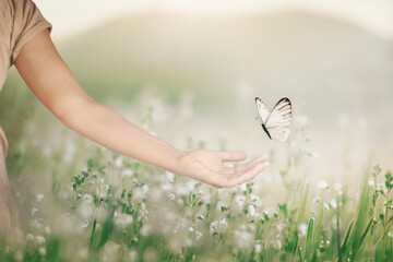 woman walking in a meadow and a butterfly approaches her hand, surreal encounter - 748259702