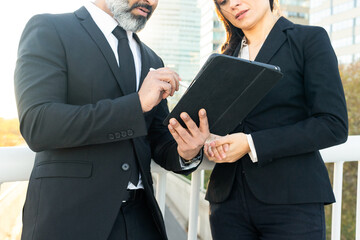 Business Colleagues Discussing Work on Tablet Outdoors