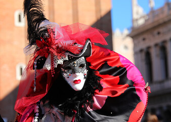 masked person during the Venice Carnival in San Marco square and the ancient buildings in the...