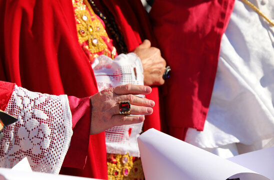 priest with a ring with a red ruby while giving the blessing to the faithful