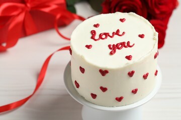 Fototapeta na wymiar Bento cake with text Love You, gift box and roses on white wooden table, closeup. St. Valentine's day surprise