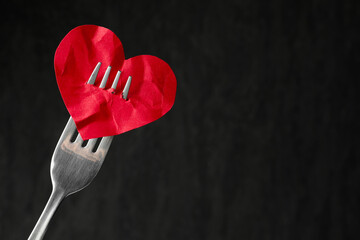 Broken heart. Red paper heart pierced with fork against black background, closeup. Space for text