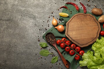 Cooking concept. Wooden cutting board and different products on grey textured table, flat lay. Space for text
