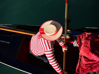 Gondolier rowing a gondola in a Venetian canal in venice in Italy
