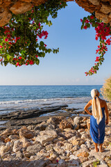 Beautiful woman in Greek attire enjoying a splendid sunrise by the sea on a summer morning