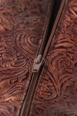 Zipper on dark brown red leather with floral print. Detail of boot.