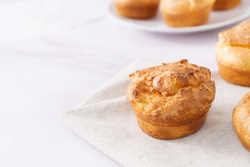 Popovers or Yorkshire pudding on linen napkin on a white background, tasty food, easy breakfast, copy space.