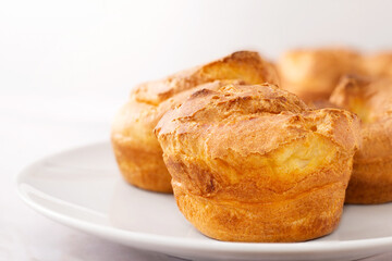Popovers on white plate on a white background,close up. Yorkshire pudding as a easy cooking breakfast, tasty food, light snack