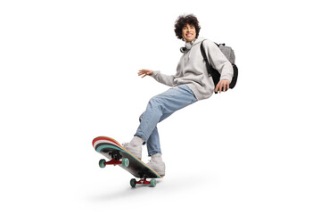 Fototapeta na wymiar Cool young man with headphones and backpack riding a skateboard