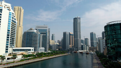 Fototapeta na wymiar Panoramic view of high buildings with glass facade. Action. Real estate business in united arab emirates and water channel.