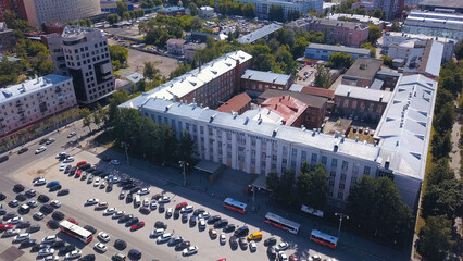 Aerial view of a summer city in rush hour. Clip. Green park zones and streets under the sun, many...