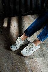 Female legs in white casual sneakers. Comfortable sports women's summer shoes.