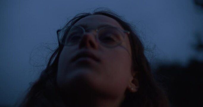 Portrait of young beautiful woman looking into the sky at twilight. Cinematic real people, empowered woman. Pensive and introvert girl in romantic atmosphere. 