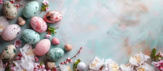 A top view of a group of colorful eggs and vibrant spring flowers arranged on a blue background, creating an Easter themed display with space for text.