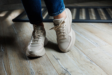 Beige women's sneakers. Collection of women's leather shoes. Female legs in leather beige casual...