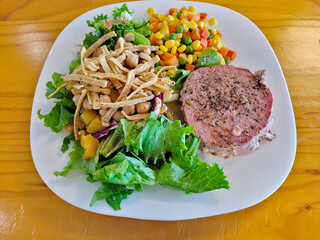 A beautifully plated seared tuna steak alongside a vibrant mixed salad and colorful corn salsa