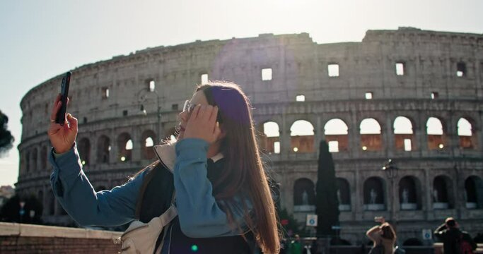 A beautiful woman tourist takes a selfie near the Coliseum. Happy moments of travel photo for memory near ancient roman architecture in rome italy. High quality 4k footage