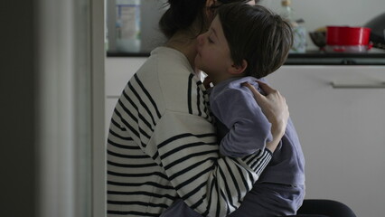 Mother consoling crying hurt little boy, candid tender moment of caring parent giving an empathic hug to upset child struggling with adversity, authentic and real life