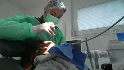 Focused Female Dentist Providing Care in Dental Clinic, Woman treating patient's oral health