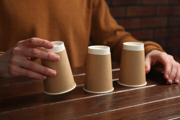 Man playing shell game at wooden table, closeup