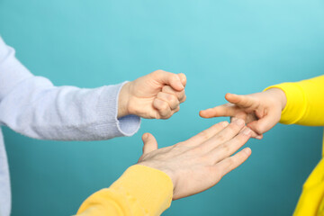 People playing rock, paper and scissors on light blue background, closeup - obrazy, fototapety, plakaty