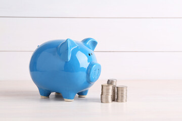 Financial savings. Piggy bank and stacked coins on white wooden table