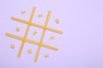 Tic tac toe game made with different types of pasta on lilac background, top view