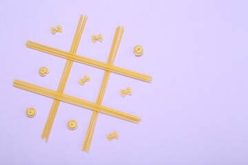 Tic tac toe game made with different types of pasta on lilac background, top view