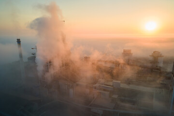 Aerial view of cement factory with high concrete plant structure and tower crane at industrial manufacturing site on foggy evening. Production and global industry concept