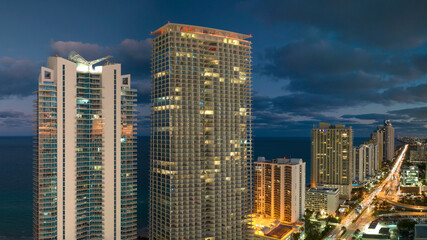 Aerial view of downtown district in Sunny Isles Beach city in Florida, USA. Brightly illuminated high skyscraper buildings in modern american midtown
