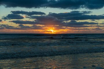 Fototapeta premium Evening landscape of sea water waves crushing on sandy beach at sunset