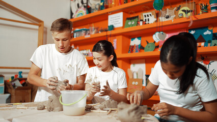 Happy diverse highschool student modeling clay at pottery workshop. Cute children with mixed raced...