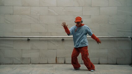 Handsome choreographer practice street dance in gray background. Young attractive b-boy dancer...