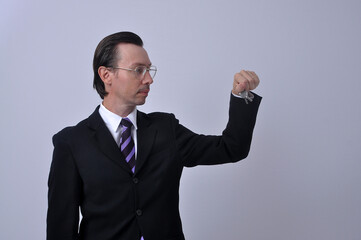 corretor de imóveis homem de negócios vestido para o comércio segurando as chaves da casa ou apartamento 