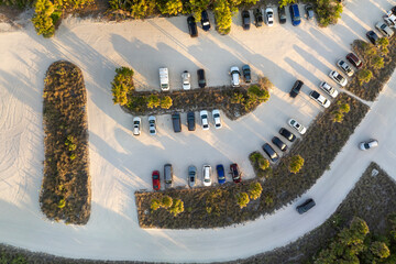 Vehicle parking area with cars parked on ocean beach parking lot at sunset. Summer vacation on...