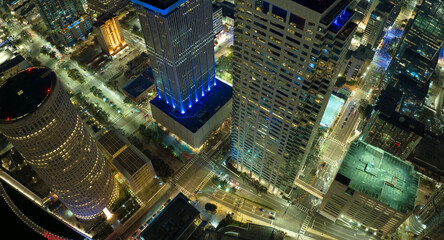 View from above of brightly illuminated high skyscraper buildings and street traffic in downtown...