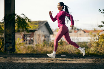 A fast sportswoman is running outdoors during her cardio training.