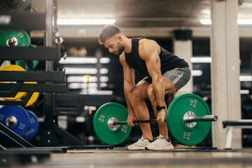 A muscular bodybuilder is doing dead lifts in a gym.