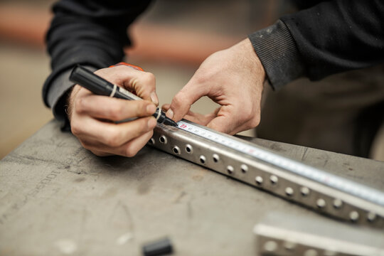 Close up of hand marking and measuring metal part.