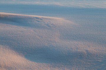 Landscape of fresh and clean snow on the ground and snowdrift at sunset. Good as a natural winter season background with copy space. Beautiful abstract snowy shapes.