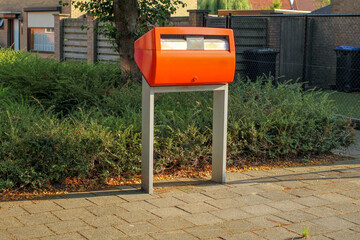 an orange public mailbox in a little village in holland