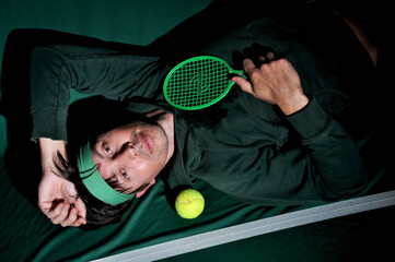 editorial homem engraçado de verde jogando tenis  - obrazy, fototapety, plakaty