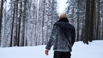 Lone man walking through snow. Media. Young guy with snow on his jacket feeling alone and isolated in cold forest.