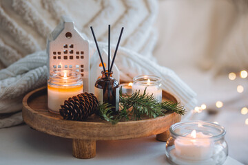 Natural Christmas essential oil, home aroma diffuser. Burning candles, branches of fir tree. Cinnamon, vanilla smell. Aromatherapy, cozy atmosphere, holiday festive mood. Close up macro, wooden table