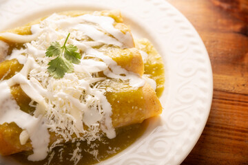 Green enchiladas. Typical Mexican dish made with a folded or rolled corn tortilla filled with...