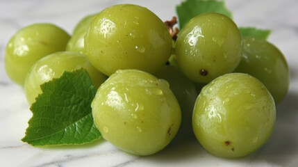 a bunch of green grapes sitting on top of a marble counter top with a green leaf on top of it.
