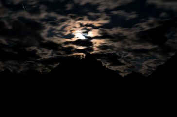 The clouds in front of the moon above the Tre Cime di Lavaredo. - obrazy, fototapety, plakaty